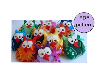 May include: A collection of colorful felt owl ornaments. Each owl has large white eyes, a red beak, and is decorated with various embellishments. The owls are in shades of blue, green, orange, yellow, and purple. A circular graphic reads "PDF pattern."