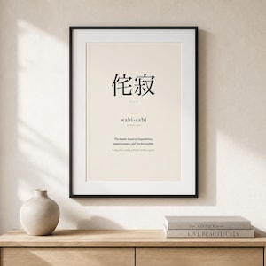 May include: A framed wall art print featuring the Japanese characters for wabi-sabi, the phonetic spelling, and the definition: The beauty found in imperfection, impermanence, and the incomplete. Nothing lasts, nothing is finished, nothing is perfect.