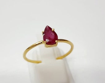 May include: A gold ring with a pear-shaped ruby gemstone.