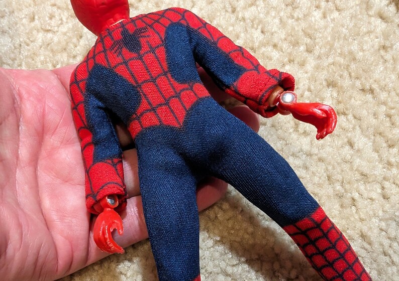Peut inclure: Une figurine d'action de Spider-Man rouge et bleue. La figurine a un motif de toile d'araign&eacute;e sur le costume et une t&ecirc;te rouge.