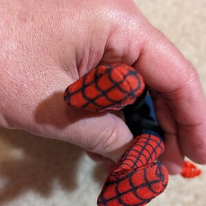 Peut inclure: Un jouet en peluche rouge et bleu en forme de Spiderman. Le jouet a un motif de toile d'araign&eacute;e sur les bras et les jambes.