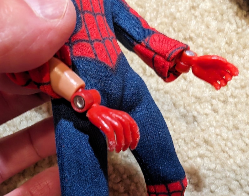 Peut inclure: Une figurine d'action rouge et bleue avec un motif de toile d'araign&eacute;e rouge sur la poitrine. La figurine a un bras et une main amovibles.