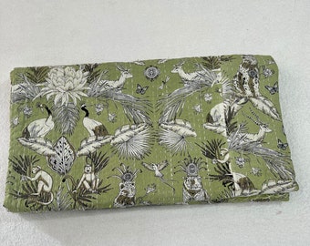 May include: A green kantha quilt with a white and black print of various animals and plants. The quilt is folded in half and has a textured surface.