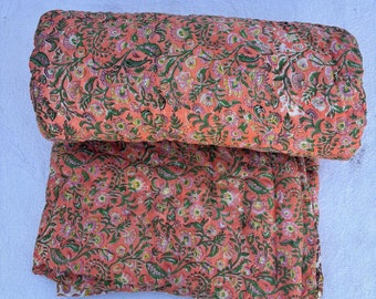 May include: A pink and green floral patterned kantha quilt. The quilt is folded in half and is made of cotton.