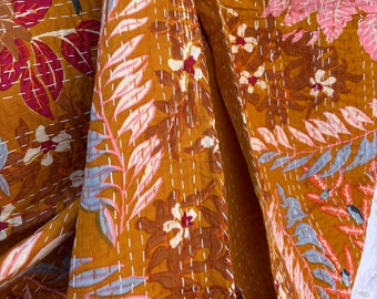 May include: A mustard yellow kantha quilt with a floral and leaf pattern in shades of pink, blue, and white. The quilt is hand-stitched with white thread.