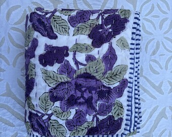 May include: A white cotton quilt with a purple floral pattern and a blue and white striped border.