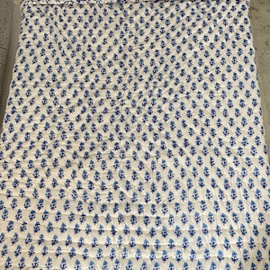 May include: A white cotton quilt with a blue floral pattern. The quilt is quilted in a diamond pattern and has a blue floral border.