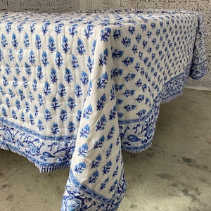 May include: White cotton tablecloth with a blue floral pattern. The tablecloth has a border with a paisley design.