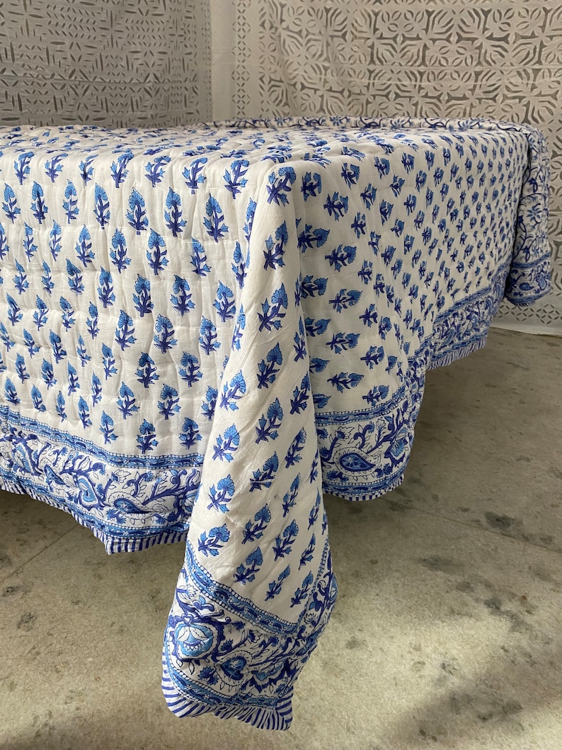 May include: White cotton tablecloth with a blue floral pattern. The tablecloth has a border with a paisley design.