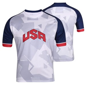 K&ouml;nnte beinhalten: Wei&szlig;es Sport-T-Shirt mit geometrischem Muster und dem Wort "USA" in roten Blockbuchstaben. Das Shirt hat marineblaue &Auml;rmel mit roten Abschl&uuml;ssen. Ein weiteres Shirt ist im Hintergrund zu sehen.