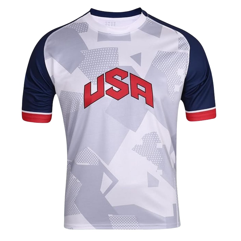 K&ouml;nnte beinhalten: Wei&szlig;es Sport-T-Shirt mit geometrischem Muster und dem Wort "USA" in roten Blockbuchstaben. Das Shirt hat marineblaue &Auml;rmel mit rotem Besatz an den Manschetten. Der Kragen ist marineblau.