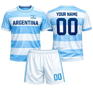 May include: A light blue and white striped football kit. The jersey displays the word "ARGENTINA" and a flag. The back of the jersey has "YOUR NAME" above the number "00". The white shorts have blue stripes and the number "00".