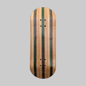 Op de afbeelding: Een fingerboard deck met een gestreept patroon. Het deck heeft afwisselende verticale strepen van lichtbruin, donkerbruin en groen hout. Er zijn vier kleine gaten geboord aan de boven- en onderkant van het deck.
