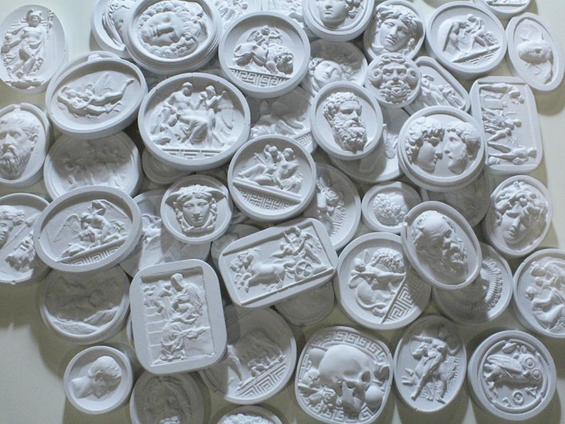 May include: A collection of white plaster relief medallions featuring various Greek and Roman mythological figures and scenes. The medallions are oval and rectangular in shape and have a raised design.