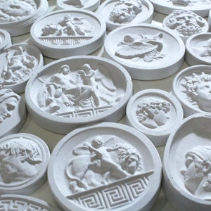 May include: A collection of white plaster round plaques with various raised relief designs of Greek mythology figures and scenes.
