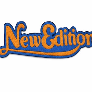 May include: Embroidered patch with the words "New Edition" in orange script lettering on a blue background. The patch has a curved shape and a stitched border, suitable for clothing or accessories.