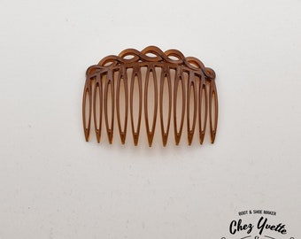 May include: A brown plastic hair comb with a decorative, wavy top. The comb has 11 teeth.