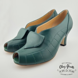 Op de afbeelding: Een paar donkergroene peep-toe hakken. De schoenen hebben een flap over de bovenkant en decoratieve stiksels. De hakken zijn middelhoog. Het merk "Chez Yvette" is zichtbaar.