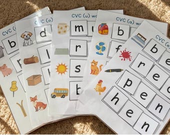 May include: A stack of educational CVC word worksheets. Each sheet features a letter and a corresponding image, such as a dog, sun, and cat. The worksheets are designed for early literacy and phonics practice.