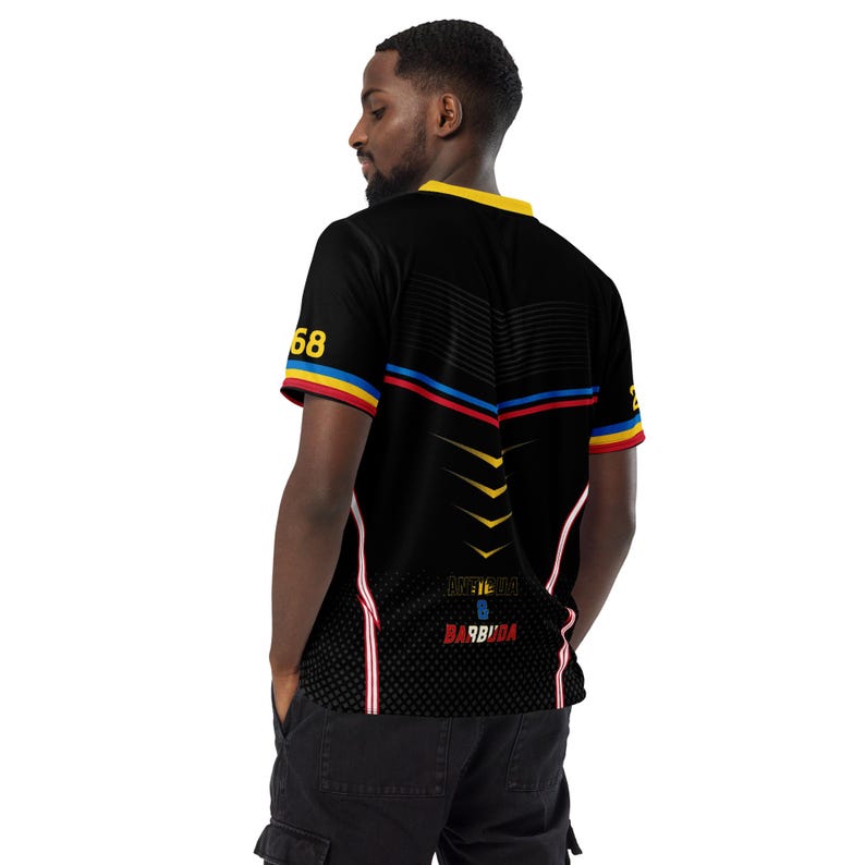 Puede incluir: Camiseta negra de manga corta con detalles amarillos, rojos y azules. La camiseta tiene un cuello amarillo y rayas rojas y azules en el pecho. El n&uacute;mero "68" est&aacute; en la manga izquierda. El texto "METEORA B BARBUDA" est&aacute; impreso en la parte trasera.