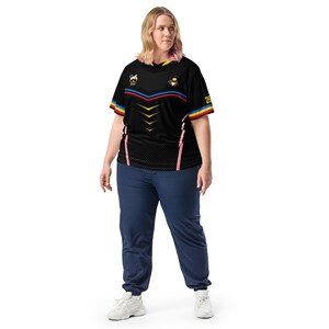 Puede incluir: Camiseta negra de manga corta con dise&ntilde;o geom&eacute;trico, detalles en rojo, azul y amarillo, y el n&uacute;mero 25. La camiseta se combina con pantalones deportivos azul marino y zapatillas blancas. La camiseta tiene un peque&ntilde;o logo en la parte superior izquierda.