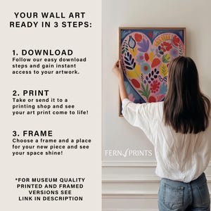 May include: A step-by-step guide on how to download, print, and frame wall art. The image shows a woman hanging a colorful heart-shaped print on a white wall. The text reads "Your Wall Art Ready in 3 Steps: 1. Download 2. Print 3. Frame" and "Fern Prints".
