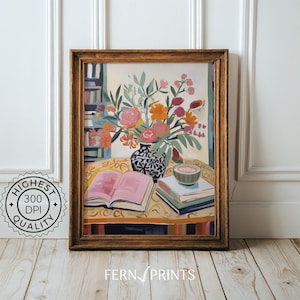 May include: A painting of a still life featuring a vase of colorful flowers, a stack of books, and a bowl on a table with a yellow tablecloth. The vase is black and white with a floral pattern. The flowers are pink, orange, and red. The books are stacked on top of each other and are brown and white. The bowl is white with a blue rim. The painting is framed in a wooden frame.