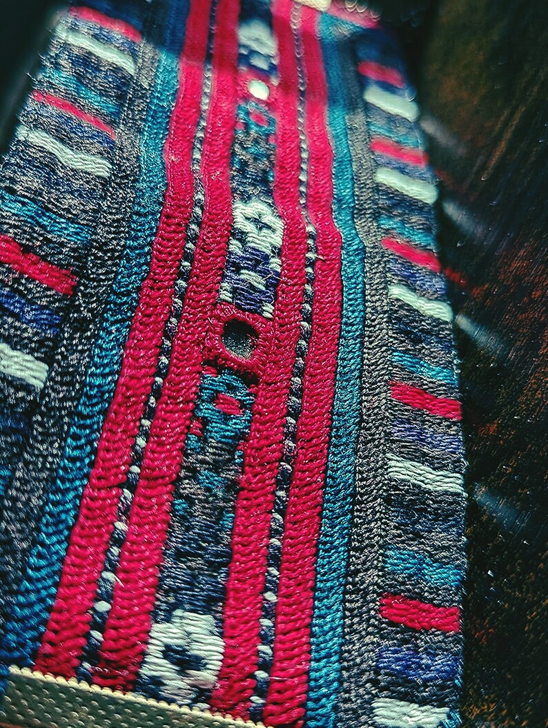 May include: Close-up of a woven fabric with a repeating pattern of red, blue, and white stripes. The fabric has a textured surface and a slightly blurred background.