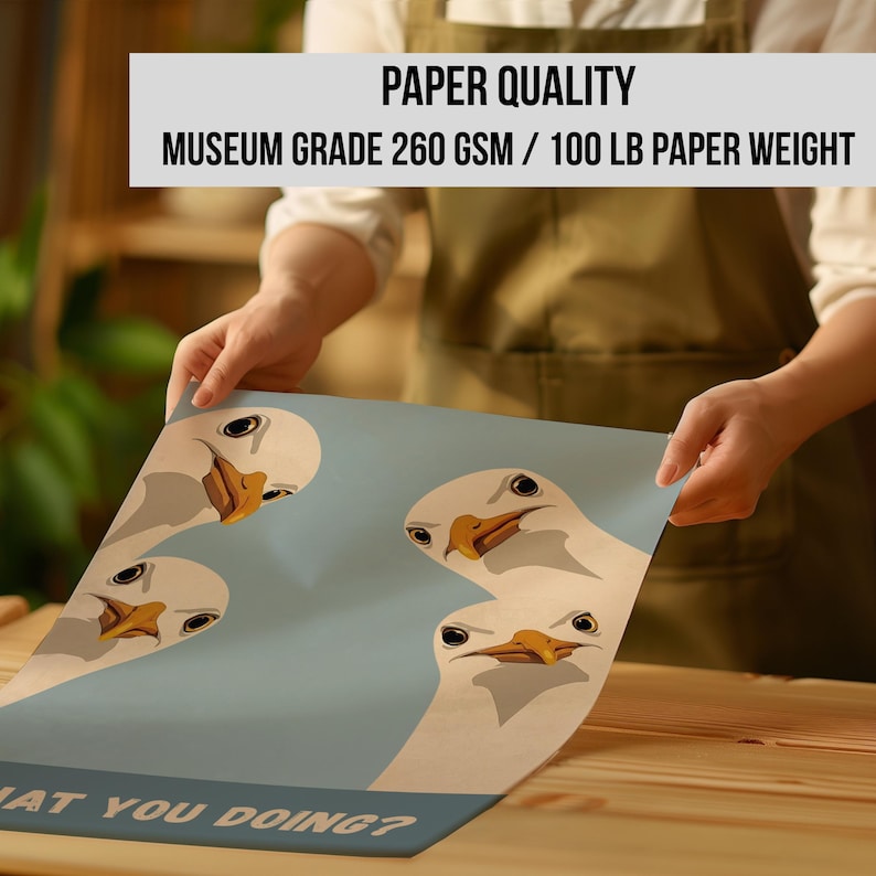 May include: A poster featuring a cartoon design of four white seagulls with orange beaks and black eyes on a light blue background. The text "WHAT YOU DOING?" is at the bottom. The poster is held by a person. The text "PAPER QUALITY MUSEUM GRADE 260 GSM / 100 LB PAPER WEIGHT" is at the top.