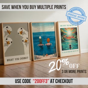 May include: Three framed art prints leaning against a wall. The prints feature illustrations of geese, people swimming in the ocean, and a tropical sunset. The prints are displayed on a wooden floor. The image includes text that says "What You Doing?" and "To Lose My Mind and Find My Soul."