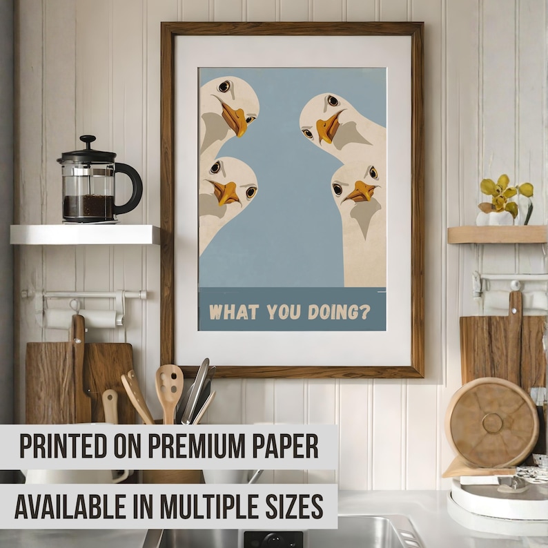 May include: Framed art print featuring four white geese with orange beaks and black eyes, set against a light blue background. The print includes the text "WHAT YOU DOING?" in a bold, white font. The frame is a dark brown color.