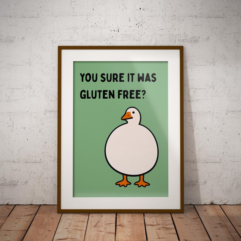 May include: A framed wall art print featuring a light green background with a cartoon illustration of a round white goose with orange feet and a beak. The black text above the goose reads, "YOU SURE IT WAS GLUTEN FREE?" in a simple font.