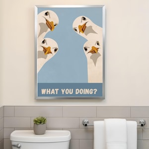 May include: A framed art print featuring four cartoon geese with white feathers and orange beaks, set against a light blue background. The text "WHAT YOU DOING?" is displayed at the bottom. The artwork is in a silver frame.