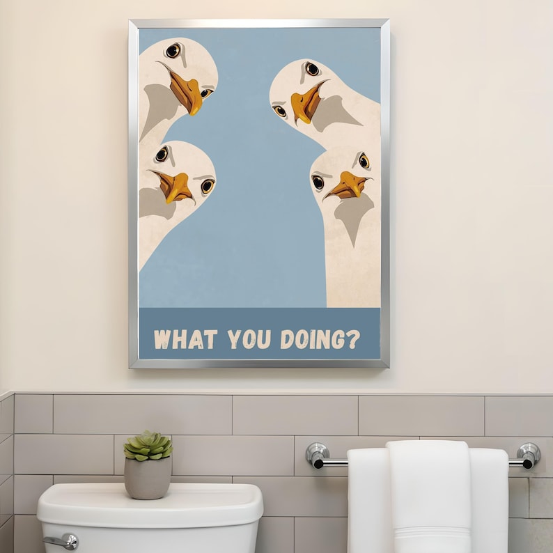 May include: A framed art print featuring four cartoon geese with white feathers and orange beaks, set against a light blue background. The text "WHAT YOU DOING?" is displayed at the bottom. The artwork is in a silver frame.