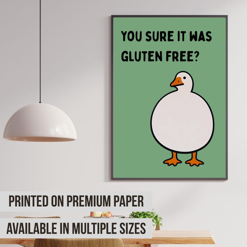 May include: A rectangular wall art print featuring a sage green background with a cartoon illustration of a round white goose with an orange beak and feet. The black text above the goose reads, YOU SURE IT WAS GLUTEN FREE? in a bold font.