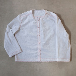 Pu&ograve; includere: Una camicia bianca a maniche lunghe con chiusura a bottoni sul davanti e cuciture rosse sui bordi. La camicia ha un collo rotondo e una vestibilit&agrave; rilassata.