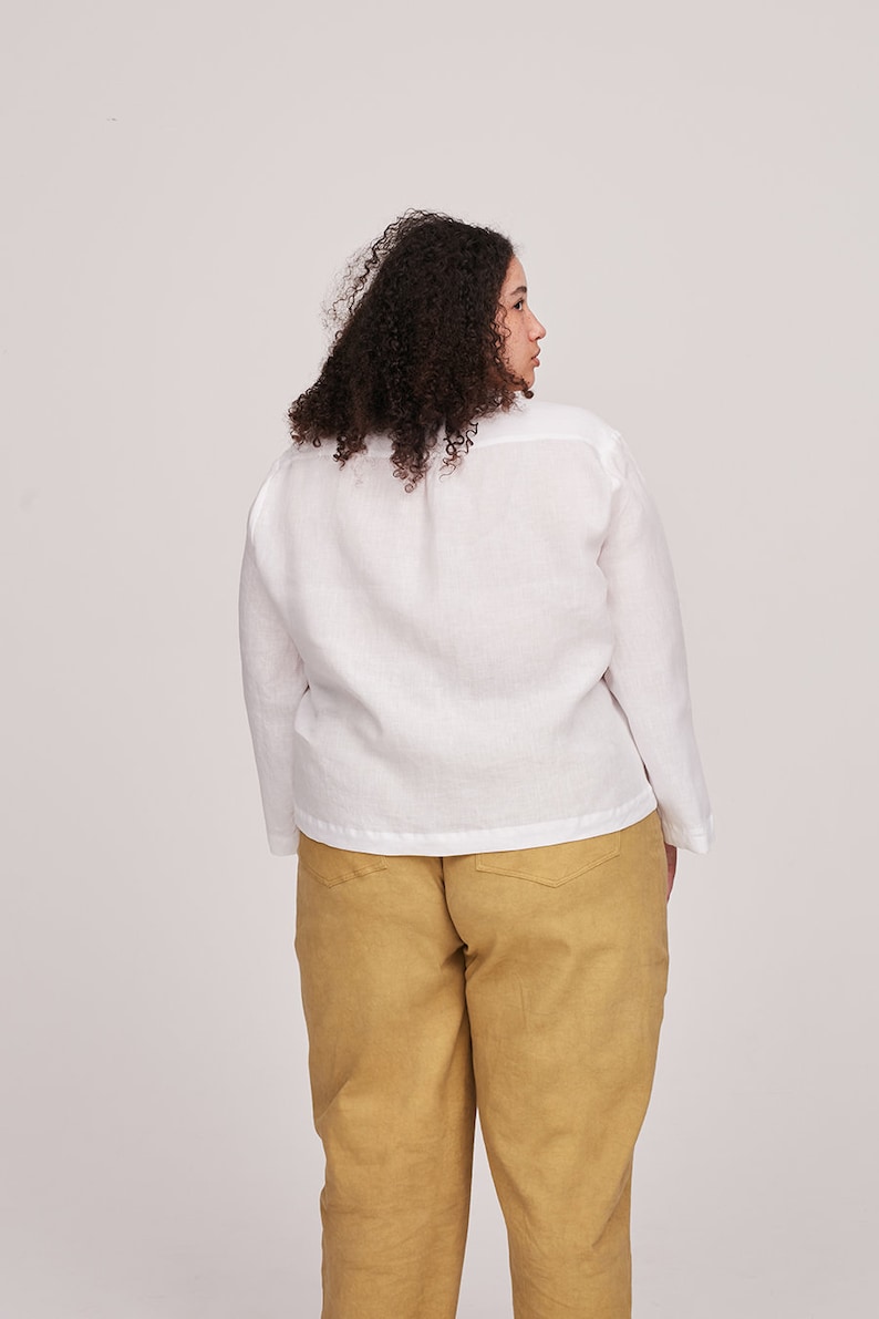Pu&ograve; includere: Una camicia di lino bianca a maniche lunghe e dal taglio ampio. La camicia &egrave; indossata con un pantalone giallo senape.