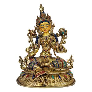 May include: A gold-colored statue of a deity, sitting in a meditative pose with hands in a mudra gesture. The statue is adorned with intricate details and colorful gemstones. The deity is wearing a crown and jewelry, and is seated on a lotus throne.