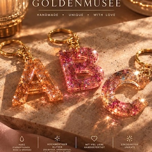 Könnte beinhalten: Drei buchstabenförmige Schlüsselanhänger A, B und C aus Harz mit eingearbeitetem Glitzer. Der Buchstabe A ist orangegold, während B und C rosa und lila sind. Jeder Schlüsselanhänger verfügt über einen Ring und eine Kette aus goldfarbenem Metall.