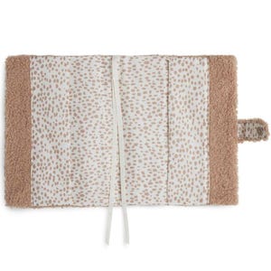May include: A beige faux fur journal cover with a white and beige spotted lining. The cover has a white ribbon closure and a beige faux fur flap with a snap closure.