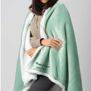 Puede incluir: Una manta de sherpa suave, verde y blanca con el texto "Mamie d'amour de Liliana & Charlie" bordado en ella.