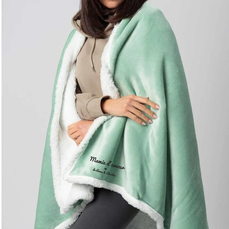 Puede incluir: Una manta de sherpa suave, verde y blanca con el texto "Mamie d'amour de Liliana & Charlie" bordado en ella.