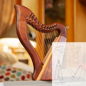 Pode incluir: Uma harpa de madeira com acabamento em madeira natural e cordas. A harpa tem 76 cm de altura e um corpo triangular. Um projeto da harpa é mostrado no fundo.