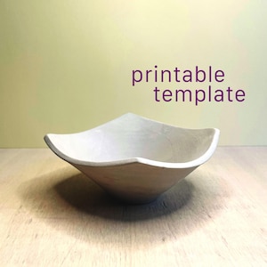 May include: A matte white bowl with a square-shaped rim and curved sides. The bowl has a smooth, solid-colored surface. The text "printable template" is displayed in purple letters above the bowl, indicating a digital design resource.