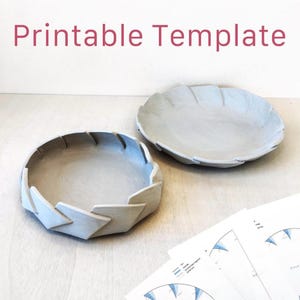 Könnte beinhalten: Ein Set aus drei Keramikbechern mit gesprenkelter, matter Oberfläche. Die Becher sind in Creme-, Hellgrau- und Dunkelgrautönen gehalten. Jeder Becher hat ein schlichtes, minimalistisches Design.