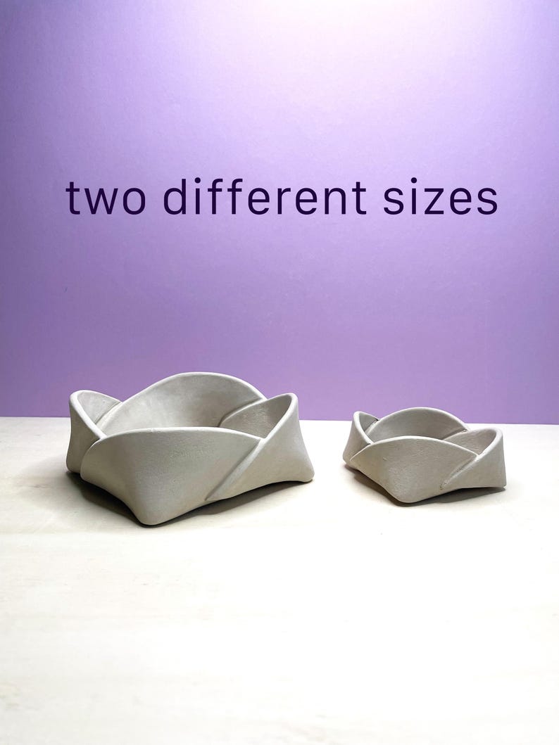May include: Two gray, folded-petal shaped bowls in different sizes. The larger bowl is on the left, and the smaller bowl is on the right. The text "two different sizes" is above the bowls.