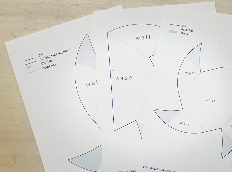 May include: Several white paper sheets with black line drawings and text, including "wall" and "base." The sheets also feature instructions: "Cut," "Cut and tape together," "Overlap," and "Guide line."