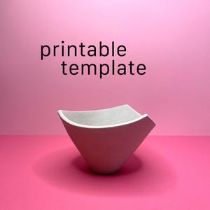 May include: A white, geometric bowl with a square top and a triangular base. The bowl is set against a pink background. The text "printable template" is above the bowl.