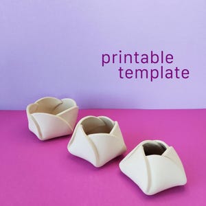 May include: Three off-white, tulip-shaped bowls arranged in a row. Each bowl features overlapping petal-like sides that create a rounded, organic form. The text "printable template" is displayed in purple letters in the upper right corner.