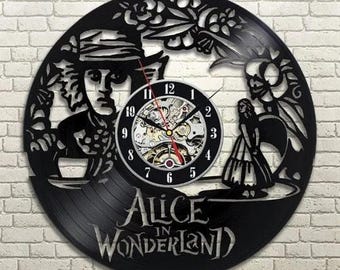 Könnte beinhalten: Schwarze Alice im Wunderland-Uhr, aus einer Schallplatte geschnitten. Die Uhr zeigt den Hutmacher, Alice und andere Charaktere. Das Zifferblatt ist schwarz mit weißen Zahlen und sichtbaren Zahnrädern. Die Worte "Alice in Wonderland" stehen unten.